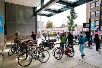 Estacionamiento para bicicletas de la estación de Link light rail con varias bicicletas y personas alrededor.
